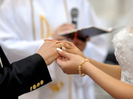 Die Braut steckt dem Bräutigam einen Ring an den Finger
