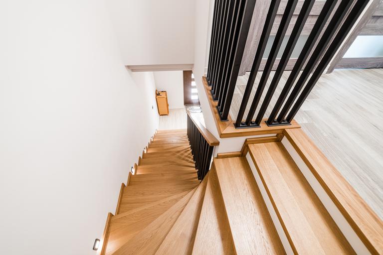 stilvolle Holztreppe in der Wohnung mit handgefertigtem schwarzem Metall