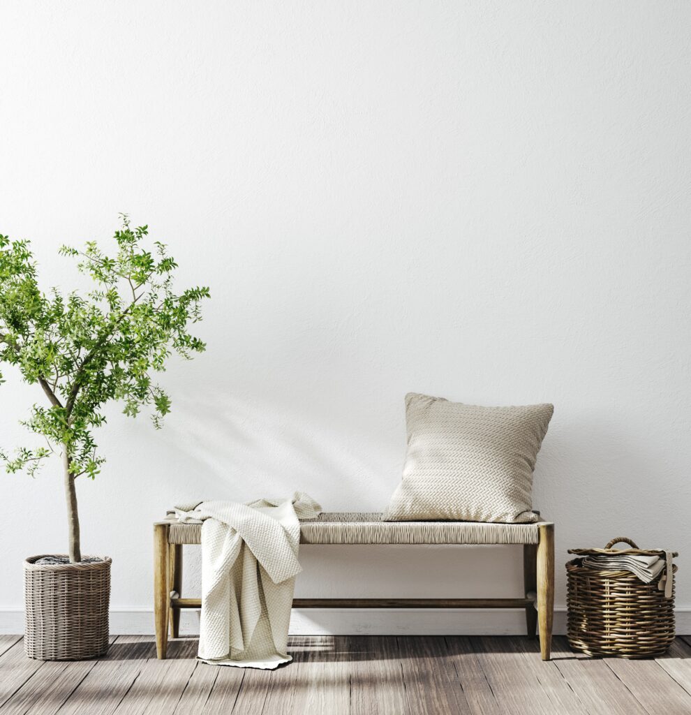 Sitzbank ohne Lehne mit Kissen und Decke in einem minimalistischen Raum, ergänzt durch einen Korb und eine Topfpflanze als dekorative Elemente