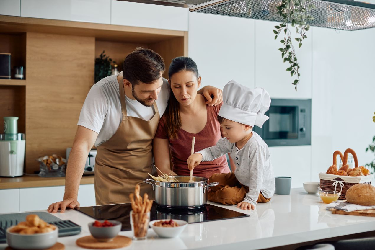 Familie kocht gemeinsam in moderner Wohnkueche mit Kind am Herd – praktische und liebevolle Ideen zum Kueche kaufen