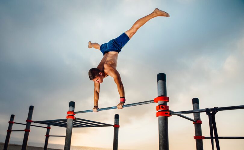 Calisthenics Training an einer Outdoor-Stange bei Sonnenaufgang am Strand