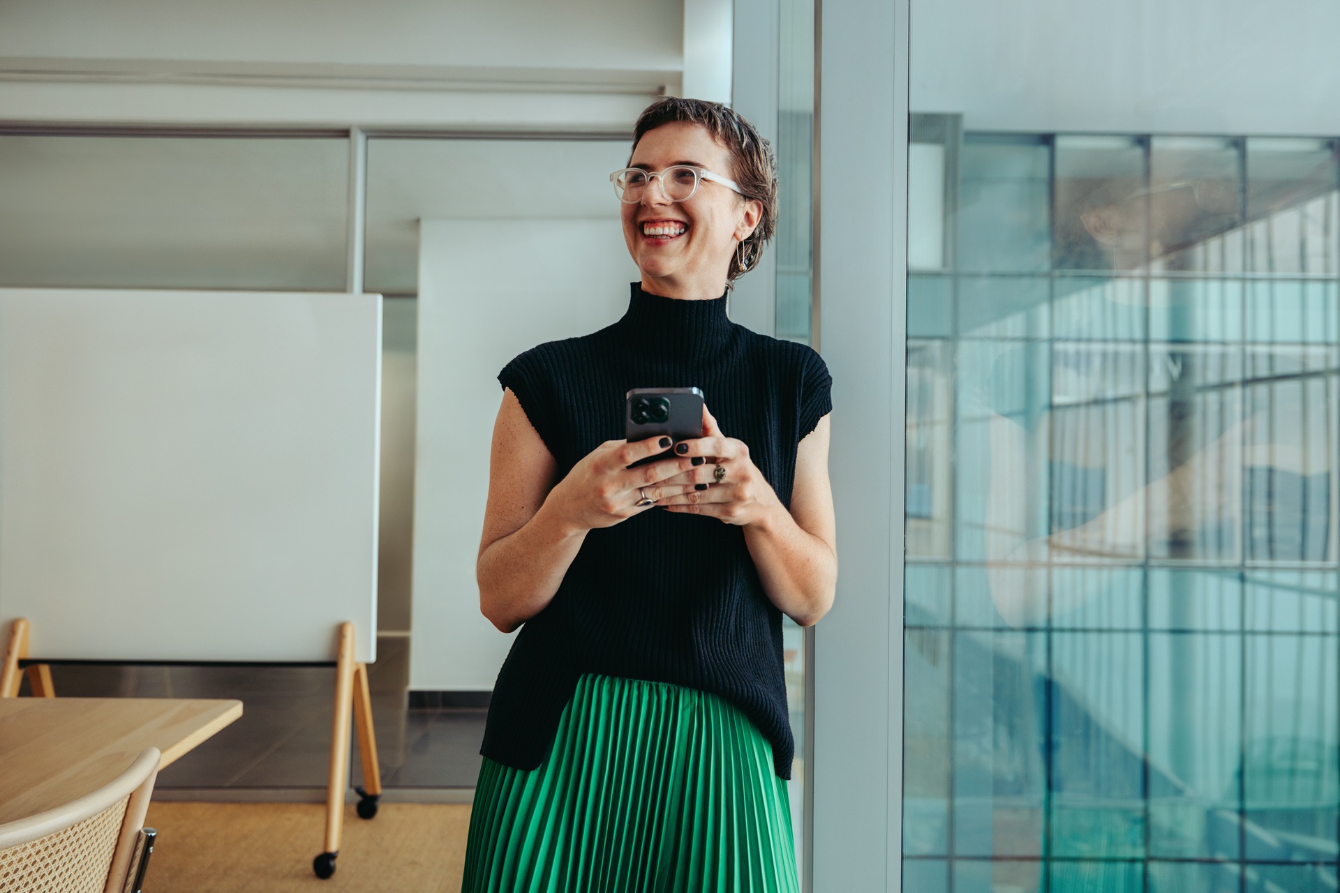 Lachende Frau mit Smartphone im Büro | Amazon Full Service Agentur